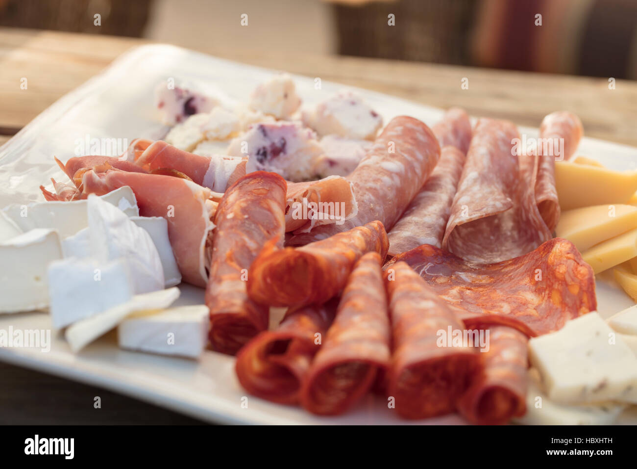 A plate of salami, sopressata, pepperoni, cheddar and brie cheeses for