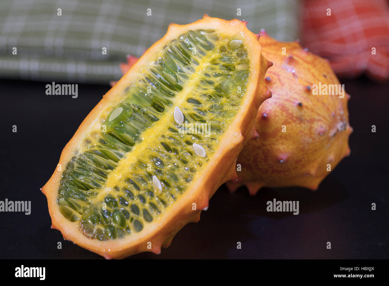 Two orange and green Kiwano Fruits set on a table top with thorny skin