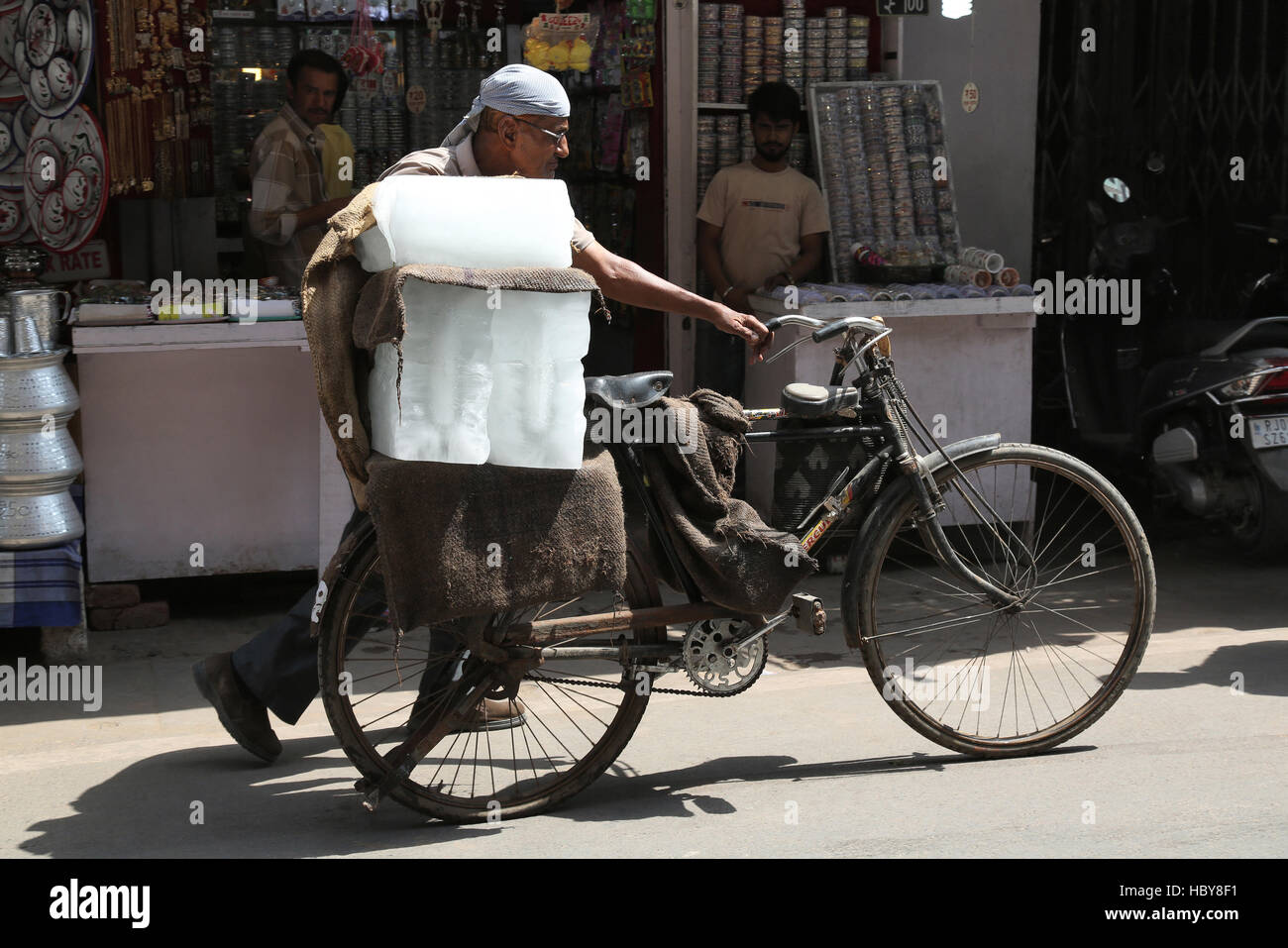 A man carrying ice blocks on a bicycle .  Ajmer market , Rajasthan, India Stock Photo