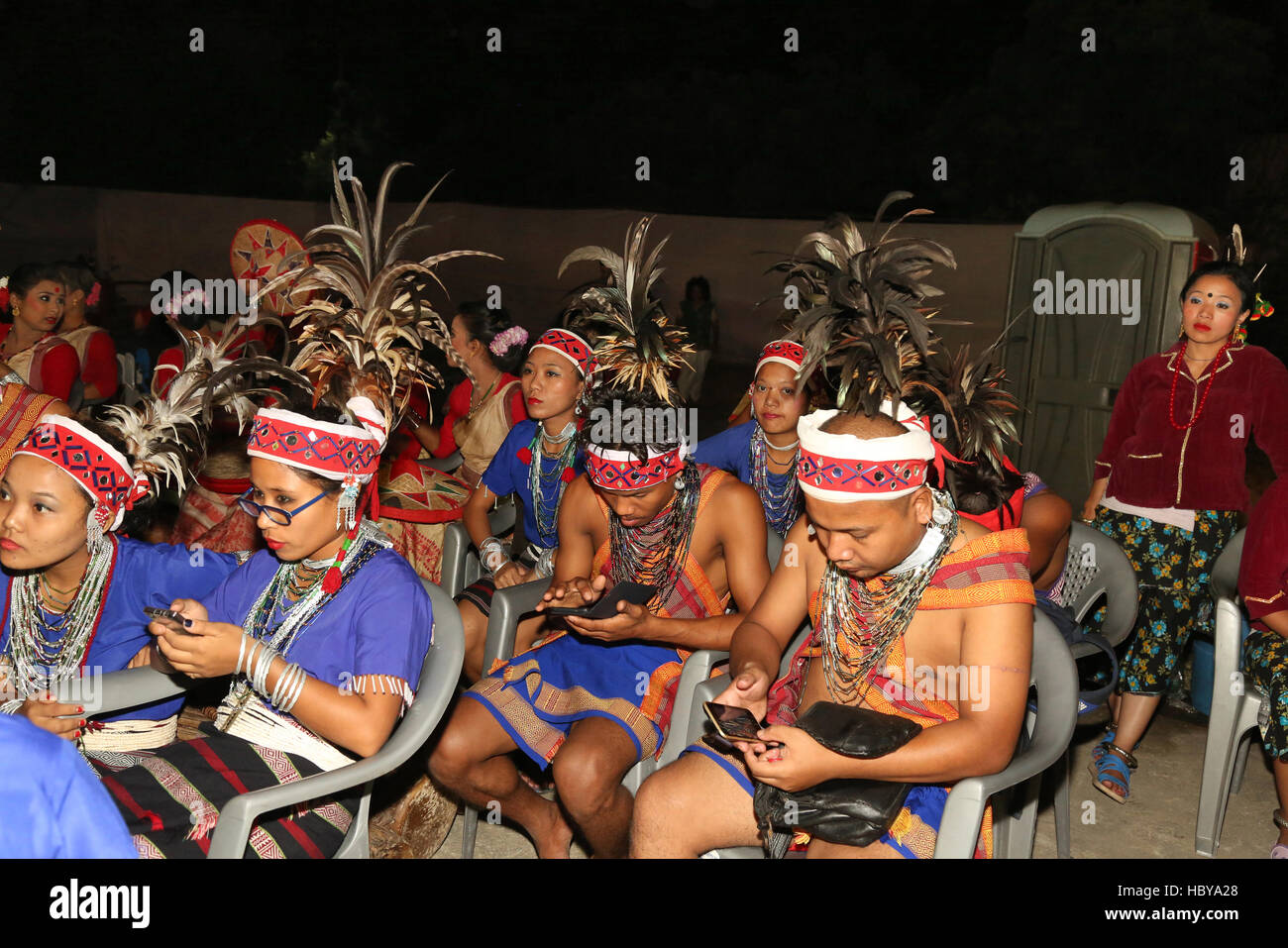 Garo Tribal dancers from Meghalaya , in India busy with mobile chatting . Ajmer, Rajasthan, India  during a tribal dance festival Stock Photo