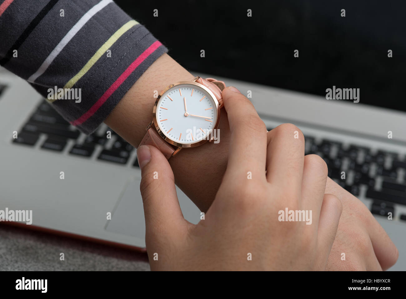 Girl's hand with wrist watch in front of notebook computer Stock Photo