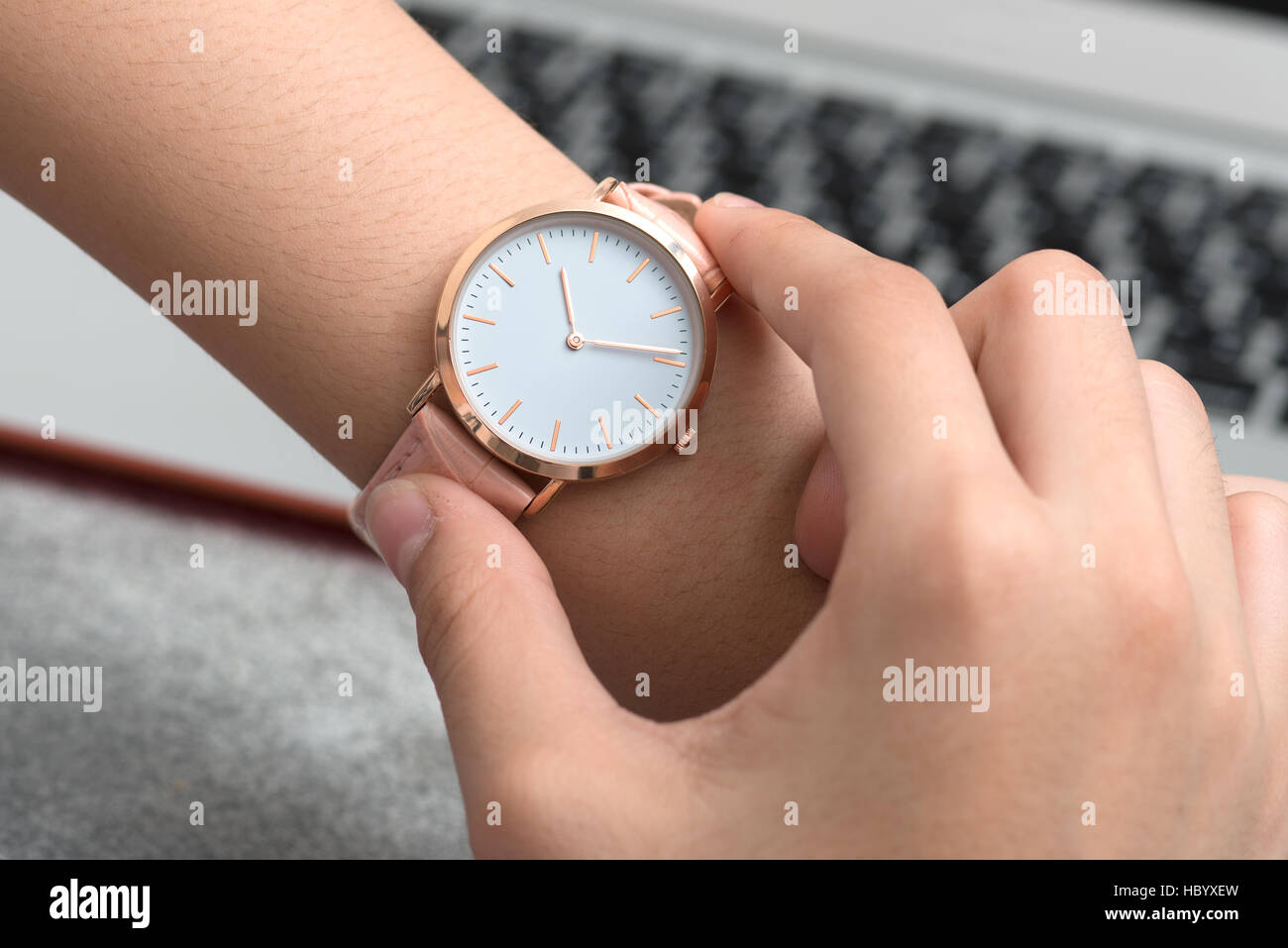 Girl's hand with wrist watch in front of desk with notebook computer Stock Photo