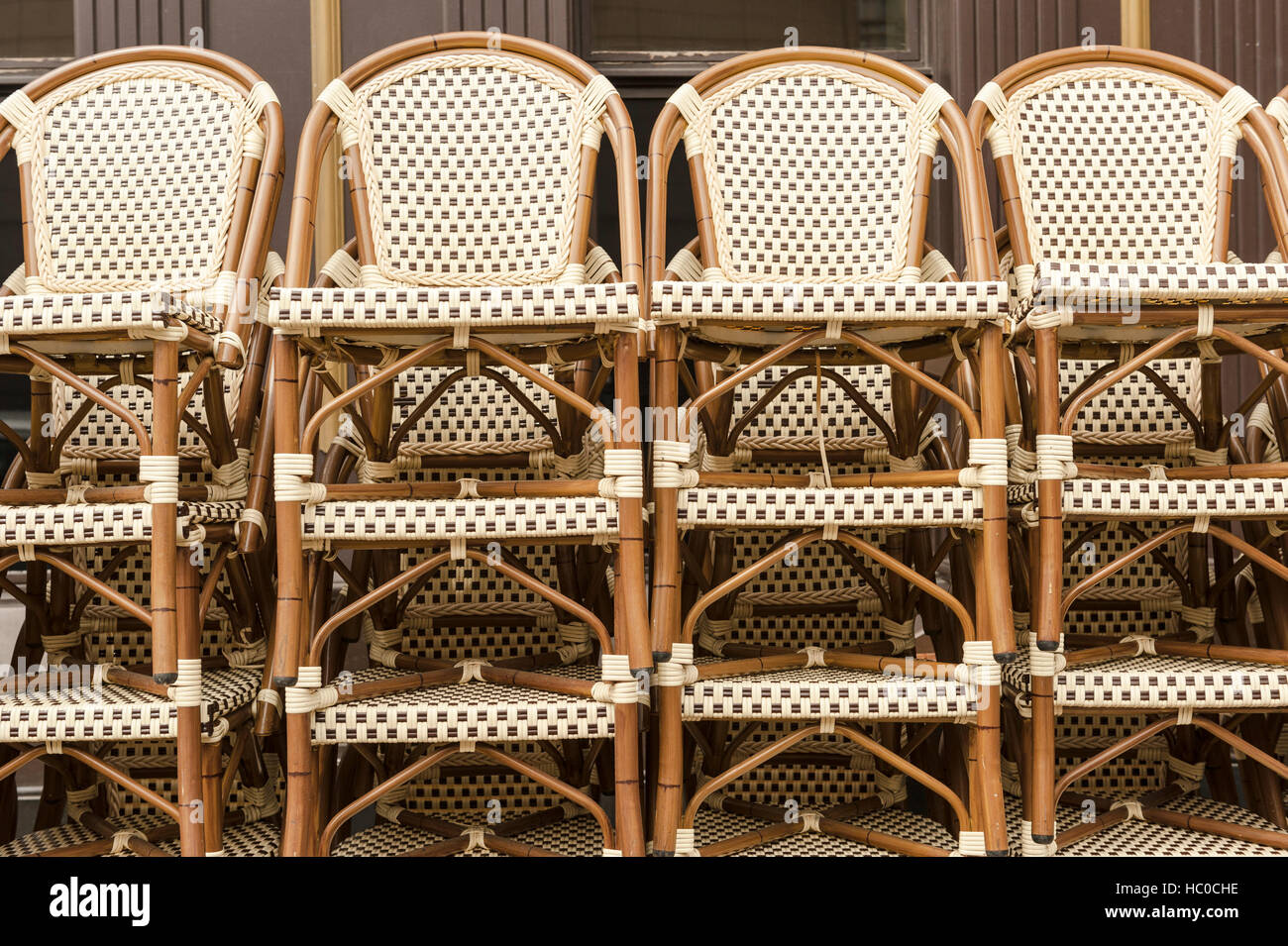 Close-up of stacks of several wicker bistro chairs on the sidewalk outside a café in Chicago, Illinois, USA. Stock Photo