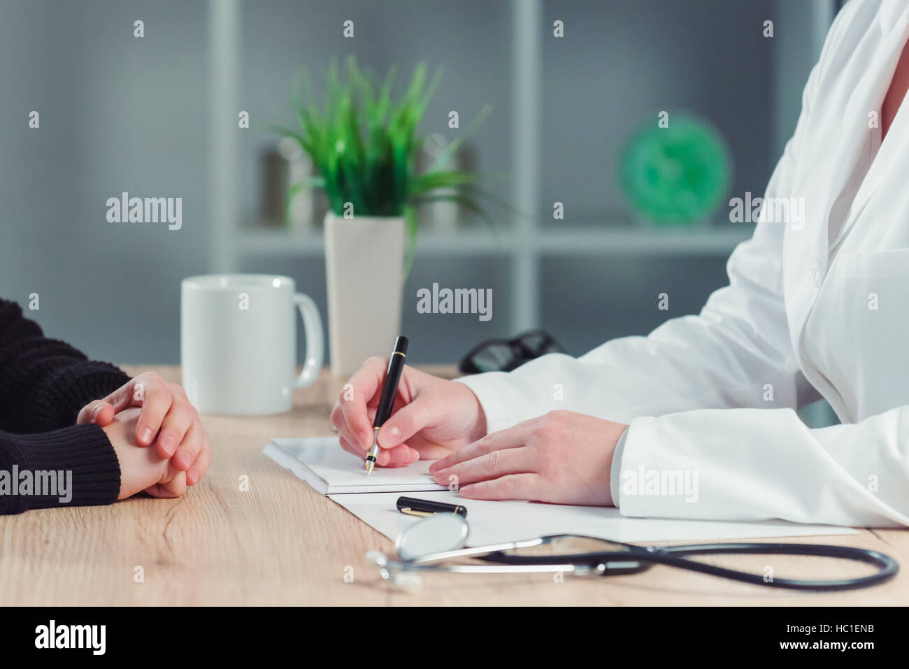 Health care and medical concept - close up of female patient and doctor hands meeting in hospital office and making appointment for medical exam. Stock Photo