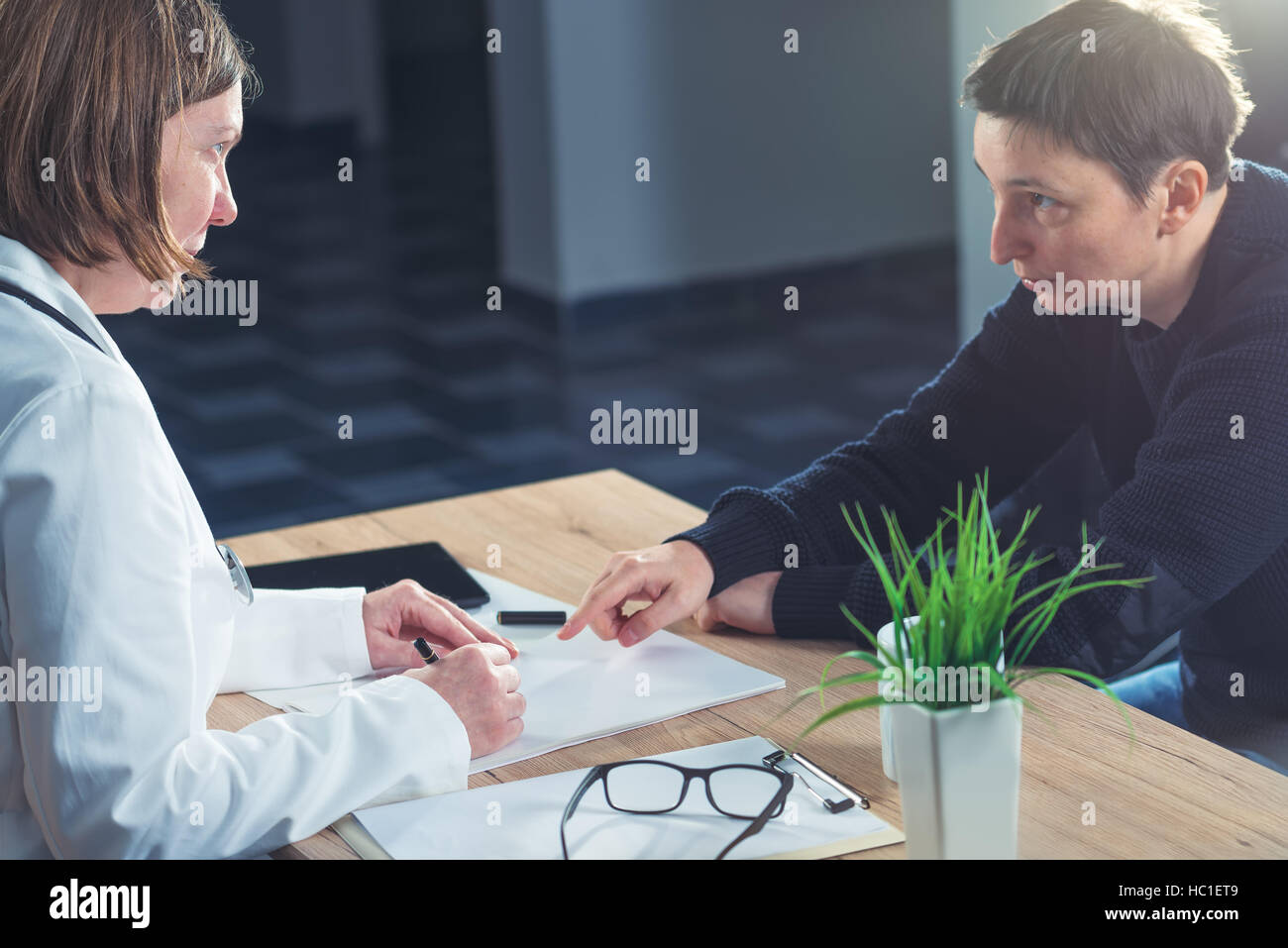 Female doctor and patient consultation during medical exam in hospital examination room Stock Photo