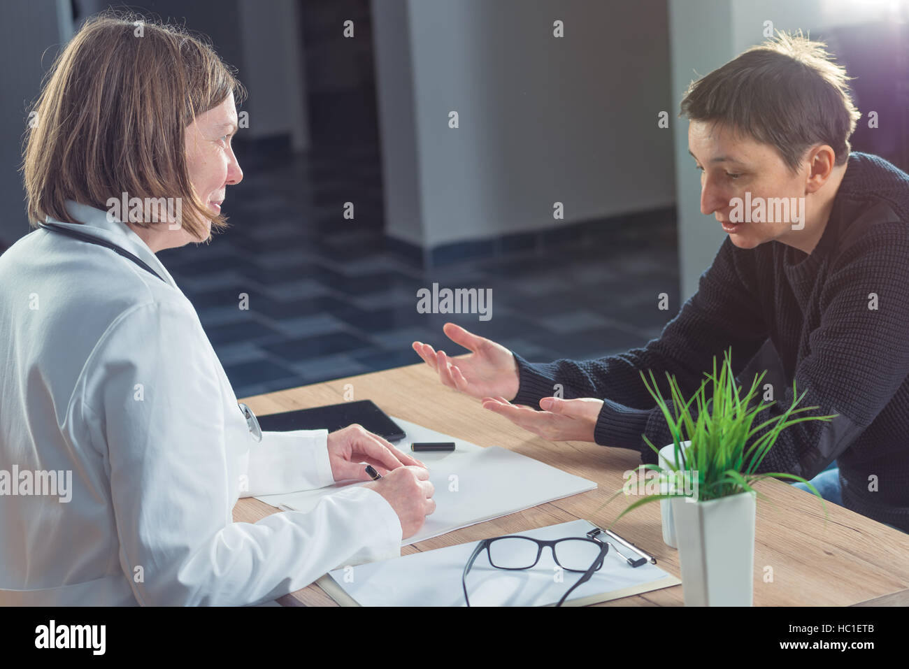Female doctor and patient consultation during medical exam in hospital examination room Stock Photo