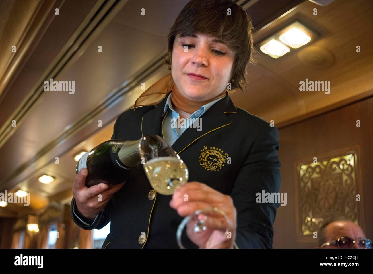 Inside of Transcantabrico Gran Lujo luxury train travellong across northern Spain, Europe. A waitress offers champagne to passengers Stock Photo