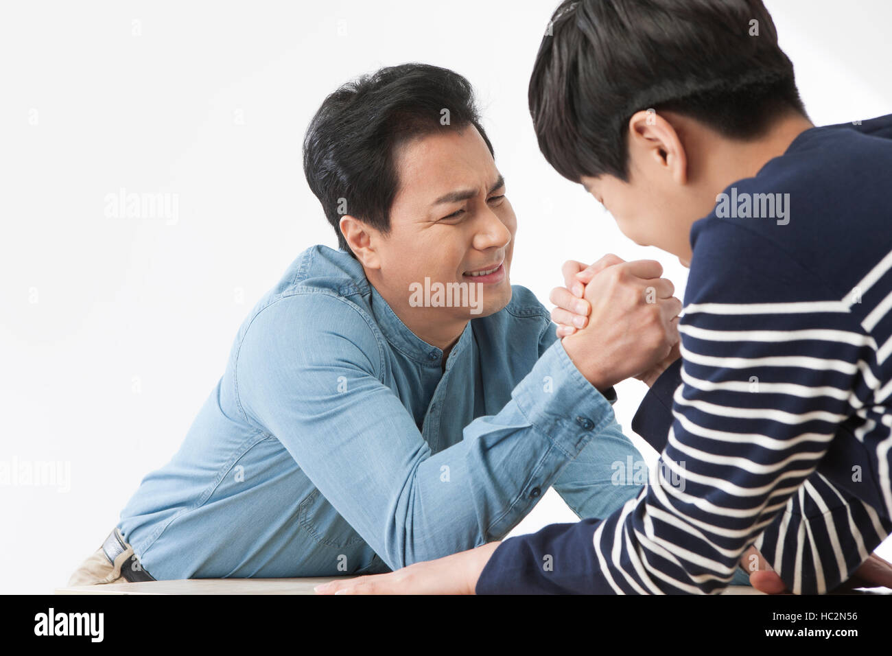 Side view of middle aged father and son arm-wrestling Stock Photo