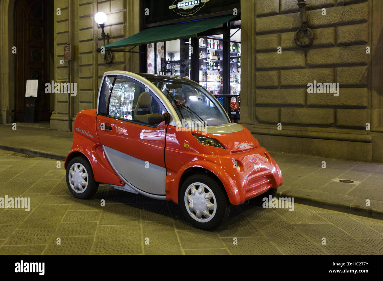 Two-seater Elettrica green car parked outside a shop at night, Via de' Tornabuoni, Florence, Tuscany, Italy Stock Photo