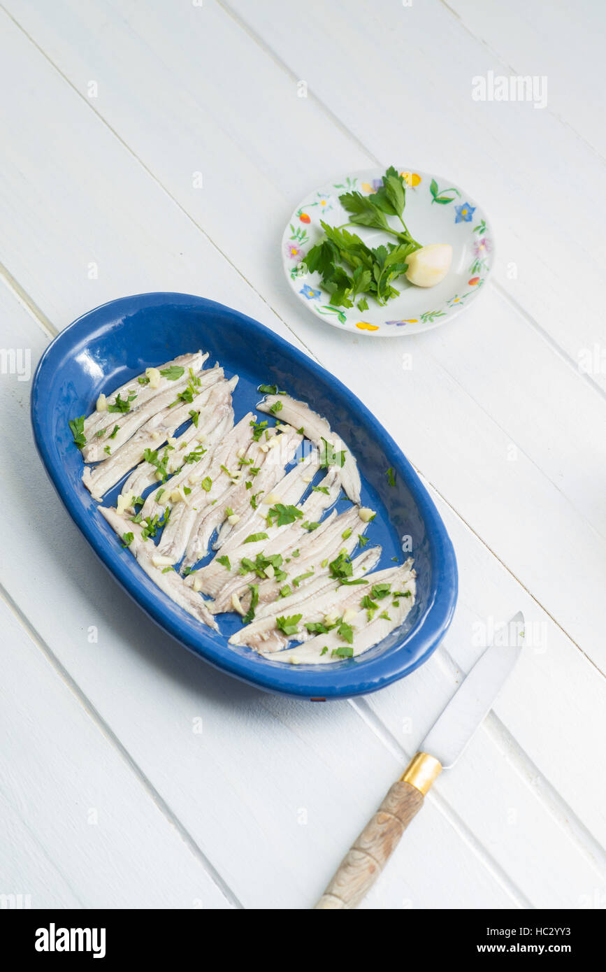 Anchovies in a blue tray on a white table Stock Photo