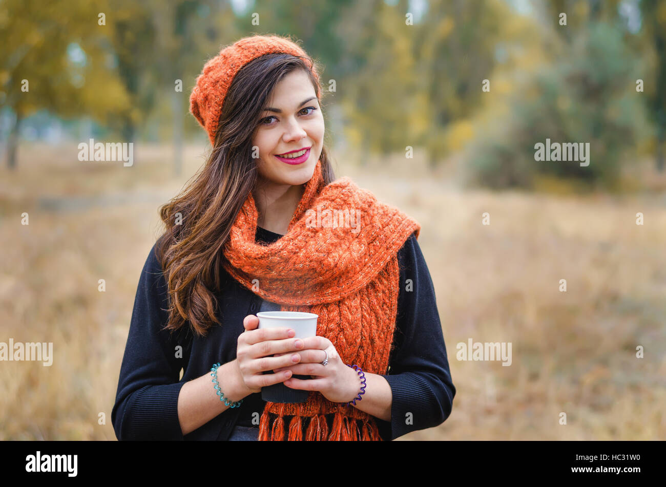 Young smiling girl with a cup of coffee (tea) for a walk in the park ...