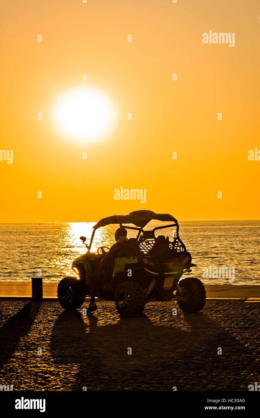 Quad motorbike by the sea at yellow sunset Stock Photo