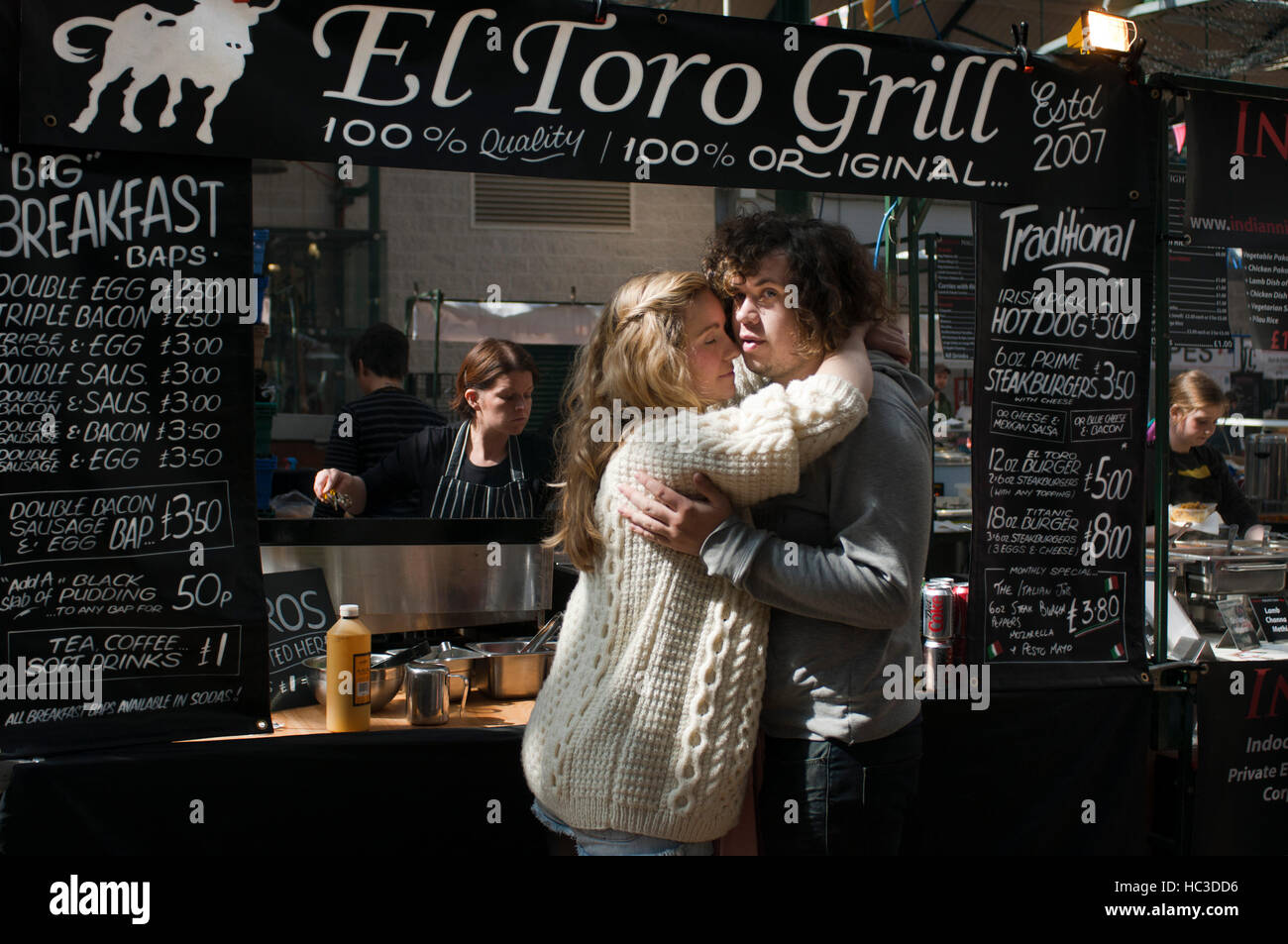 A couple embraces each other in Toro Grill Restaurant Inside St. George’s Market, Belfast, Northern Ireland, UK. St George’s Market is one of Belfast’ Stock Photo