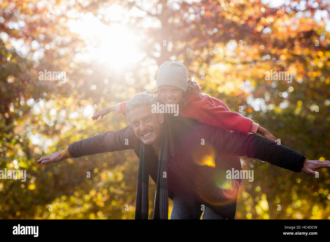 Playful father carrying daughter on back at park Stock Photo - Alamy