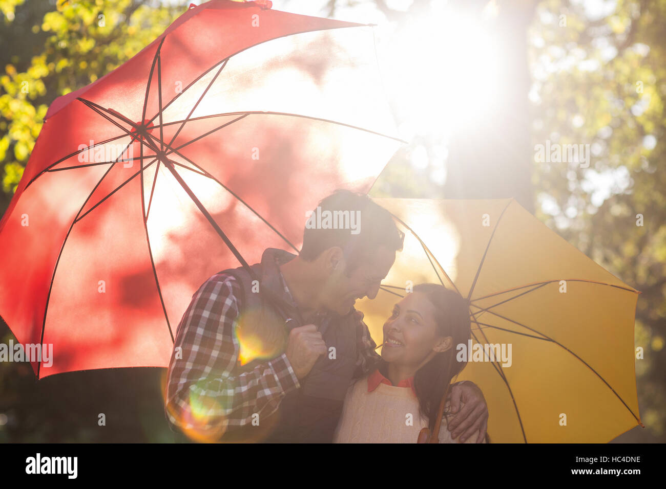 Romantic couple with umbrellas at park Stock Photo - Alamy