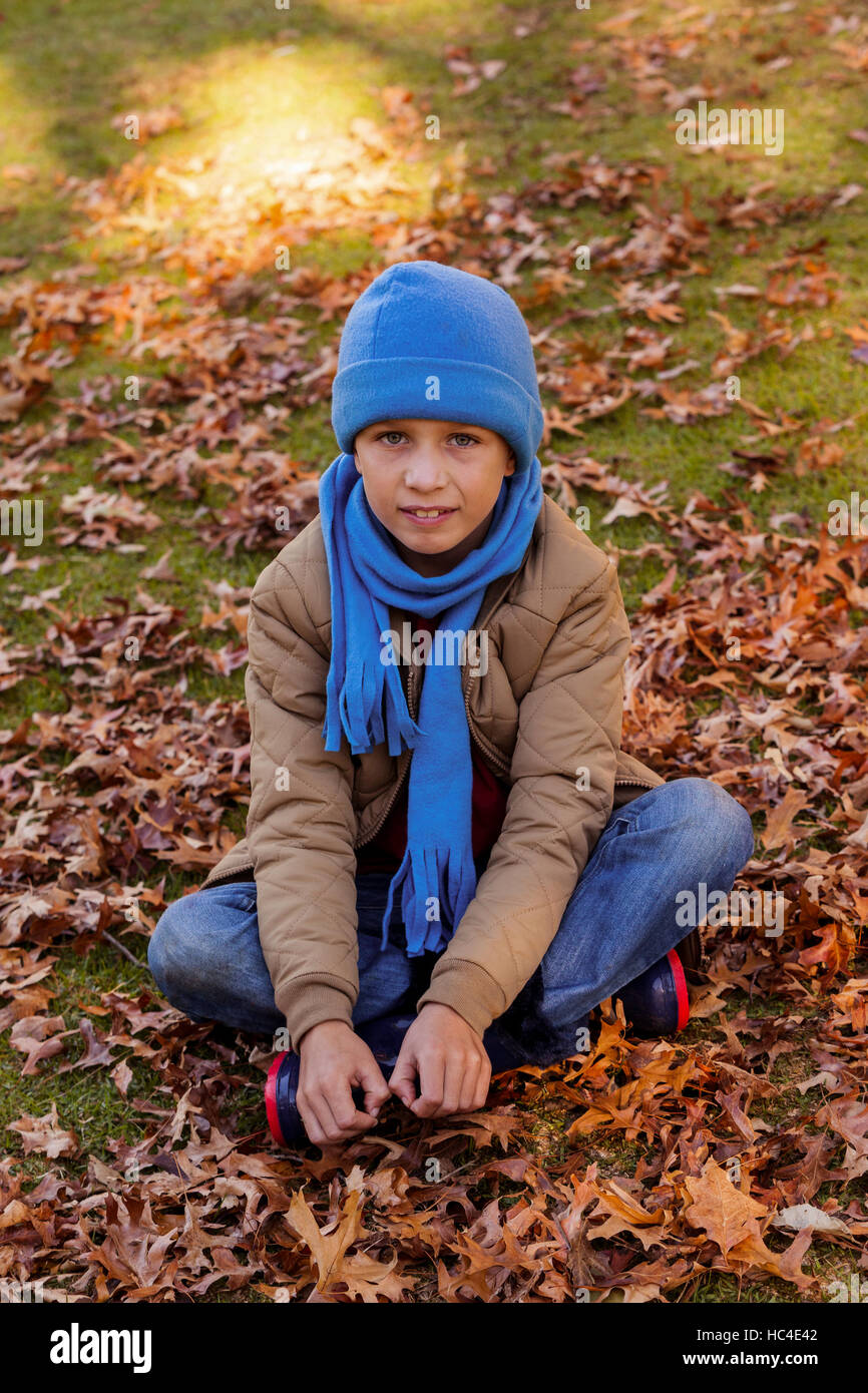 Portrait of smiling boy sitting at park during autumn Stock Photo - Alamy