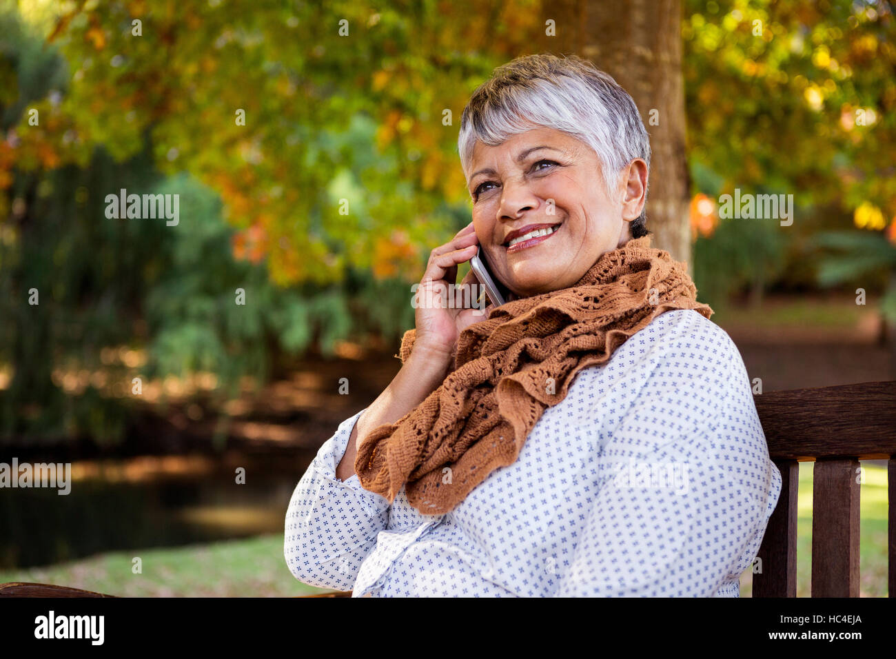 Mature woman talking on cellphone at park Stock Photo - Alamy