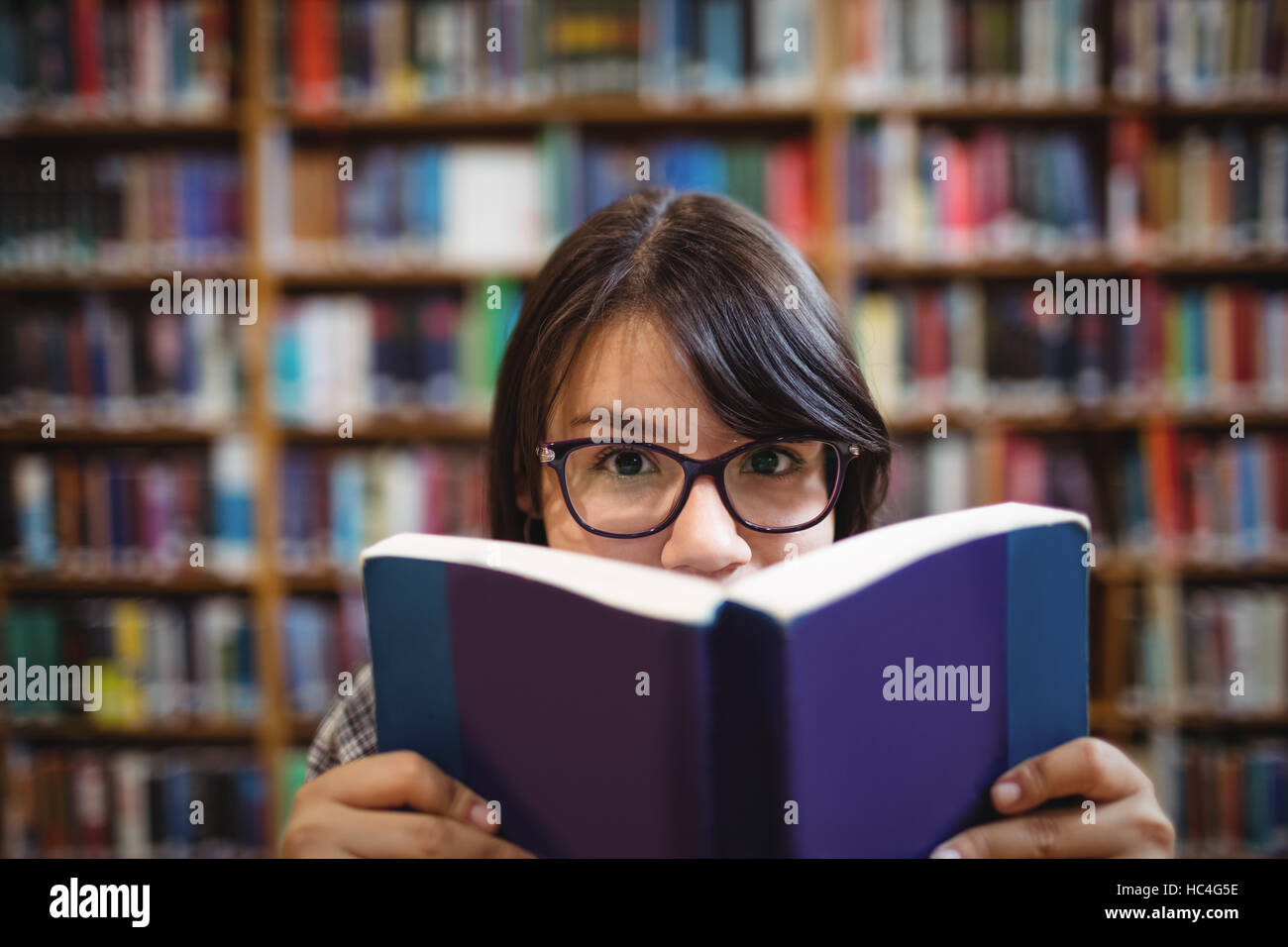 Female student holding book in college library Stock Photo - Alamy