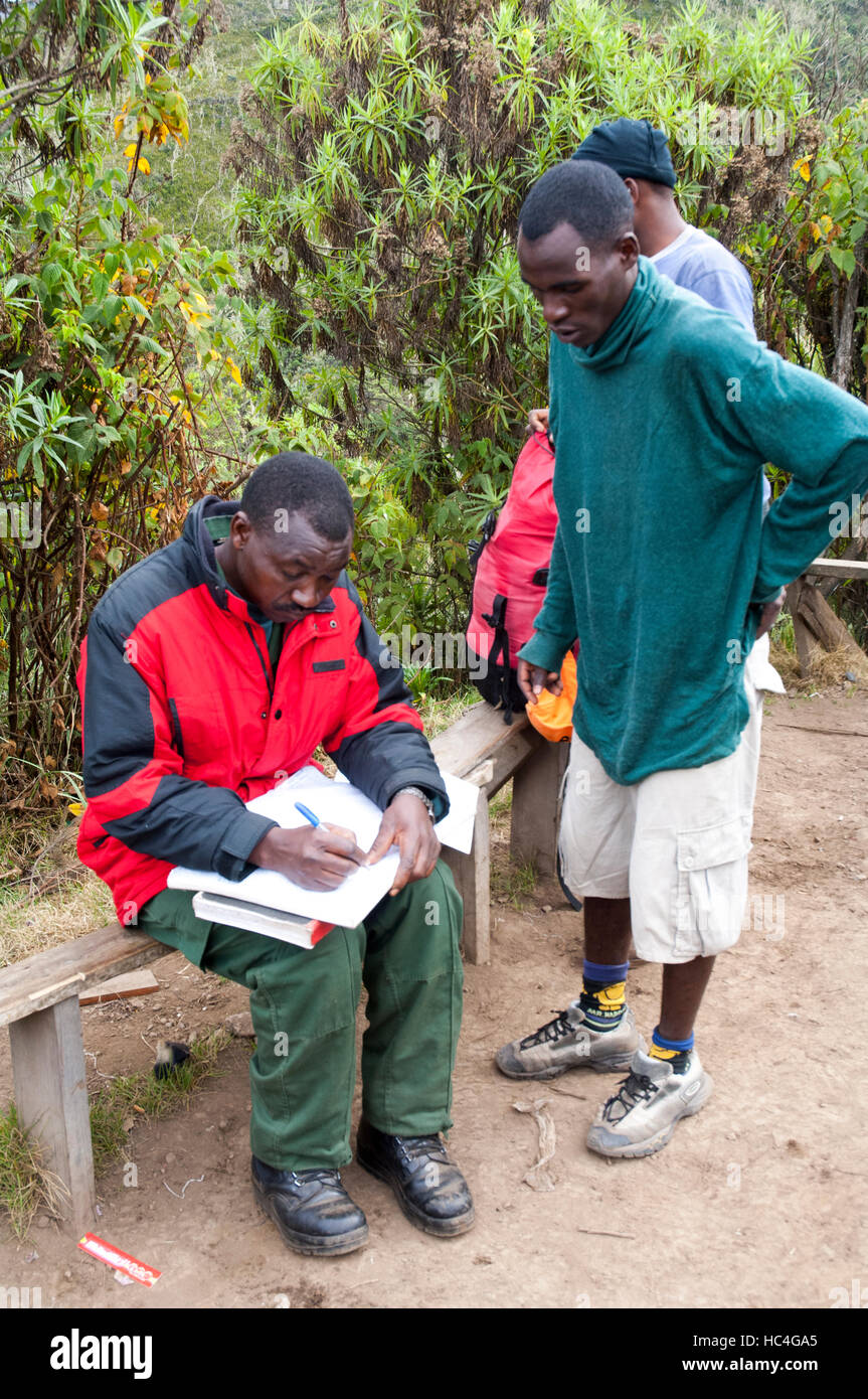 Porter with permit reports to park warden on arrival at Machame hut, Kilimanjaro, Tanzania Stock Photo