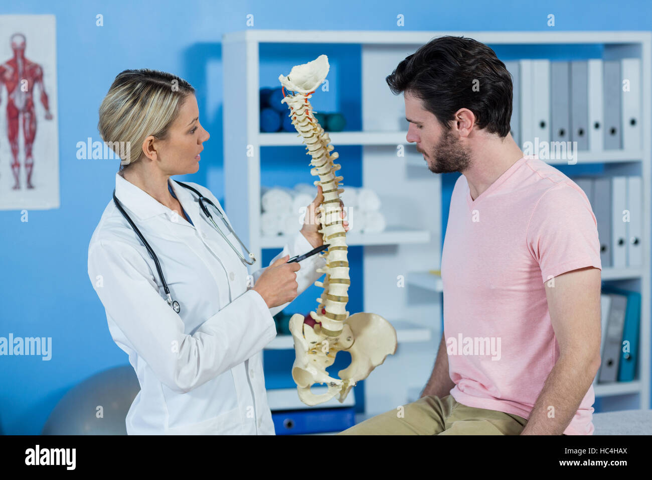 Physiotherapist explaining the spine model to patient Stock Photo