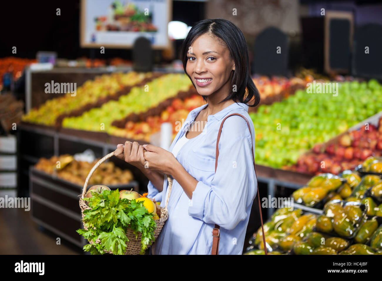 Smiling woman holding fruits and vegetables in basket Stock Photo - Alamy