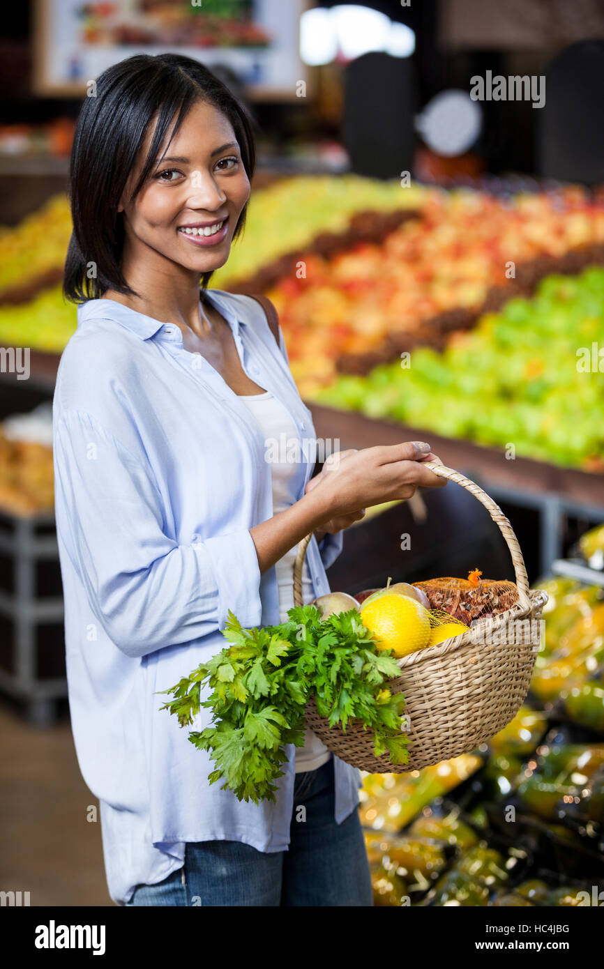 Smiling woman holding fruits and vegetables in basket Stock Photo - Alamy
