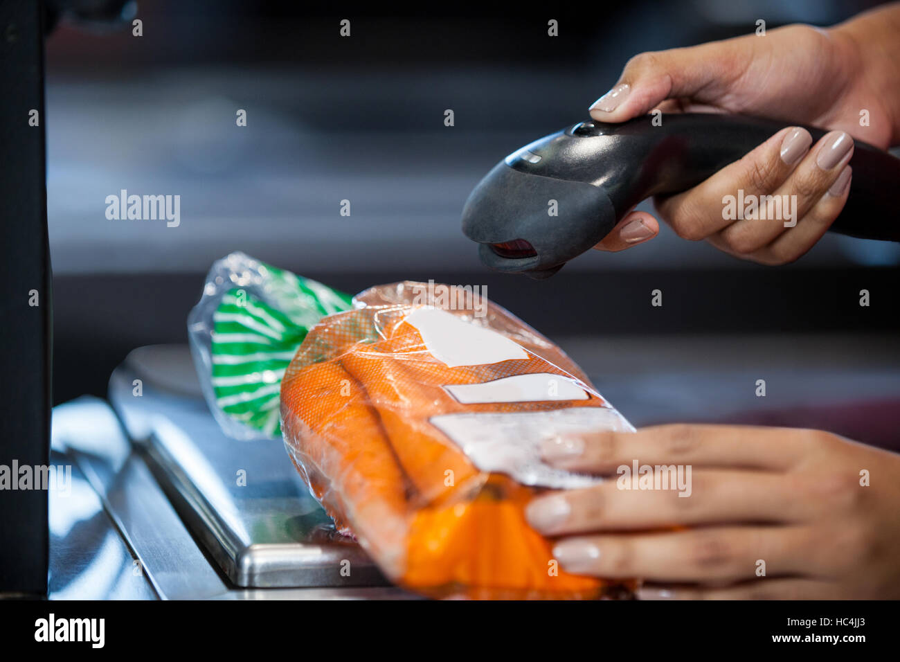 Woman scanning goods at checkout counter Stock Photo