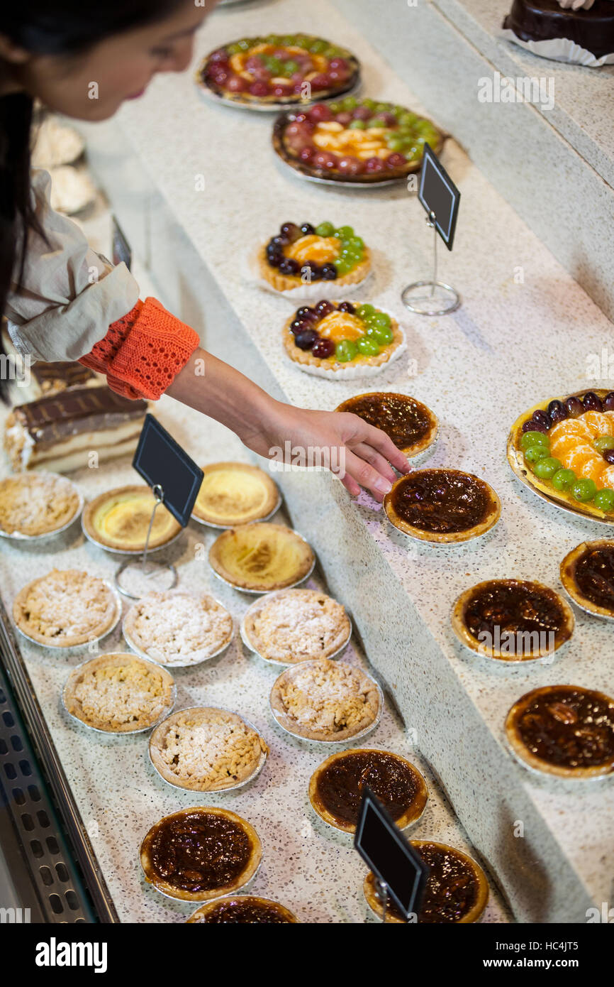 Woman selecting tart from display Stock Photo