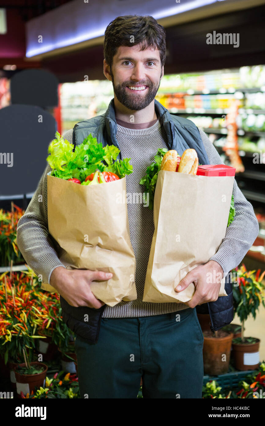 Portrait of smiling man holding a grocery bag in organic section Stock Photo
