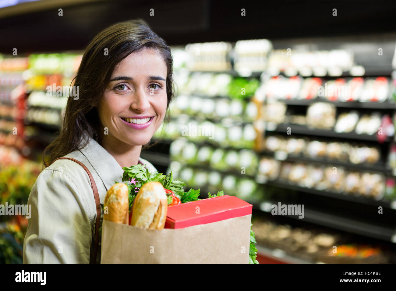 Portrait of smiling woman holding a grocery bag in organic section Stock Photo
