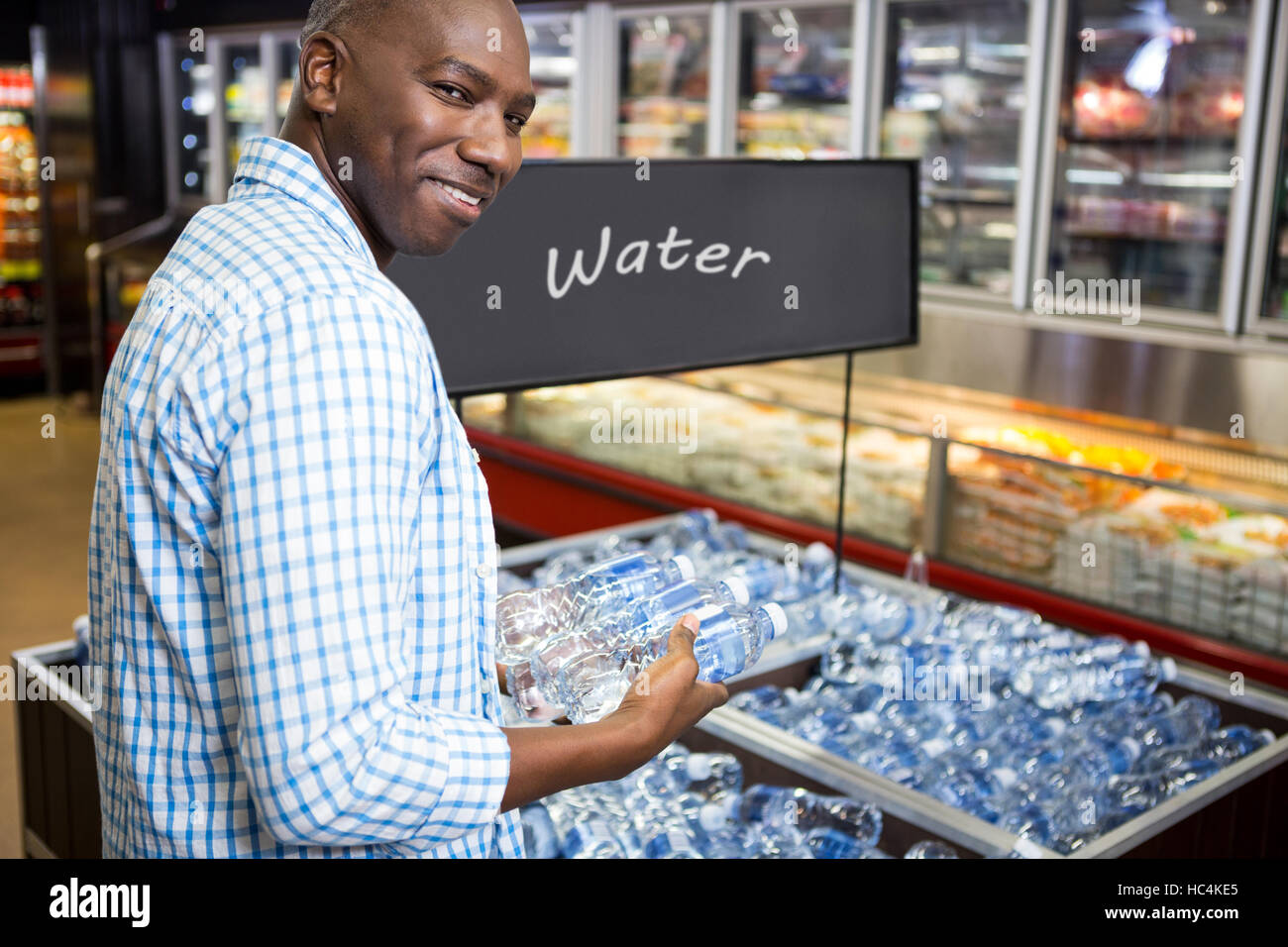 Man looking at bottle of water in supermarket Stock Photo