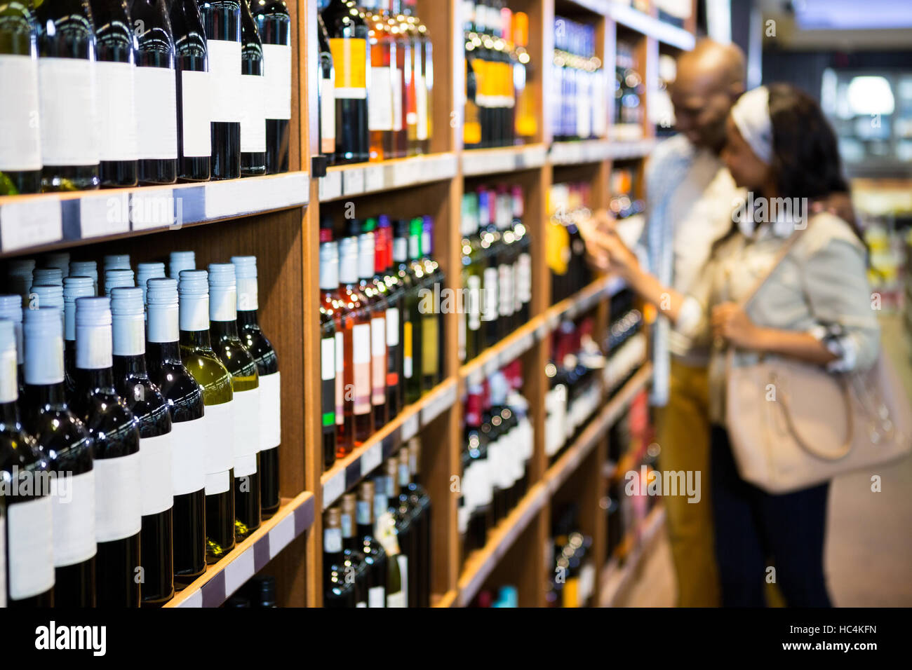 Couple looking at wine bottle in grocery section Stock Photo