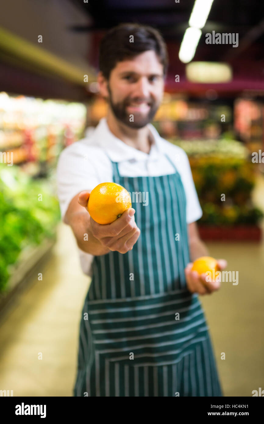 Smiling male staff showing fruit in organic section of supermarket Stock Photo