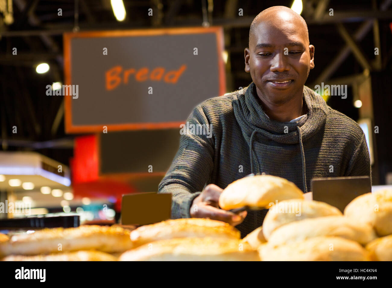 Man buying croissant bread from display counter Stock Photo