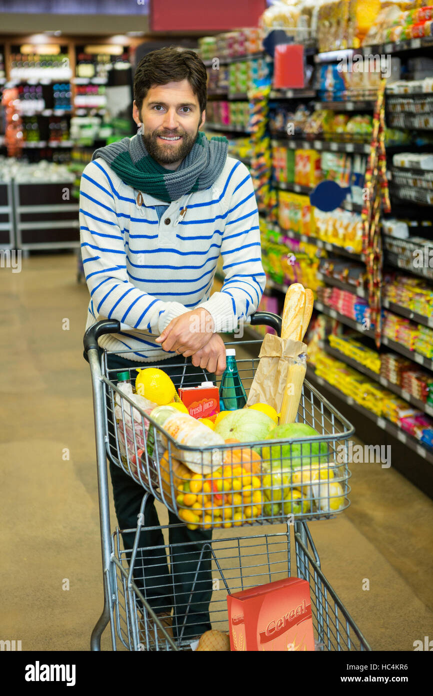 Portrait of smiling man with trolley in grocery section Stock Photo