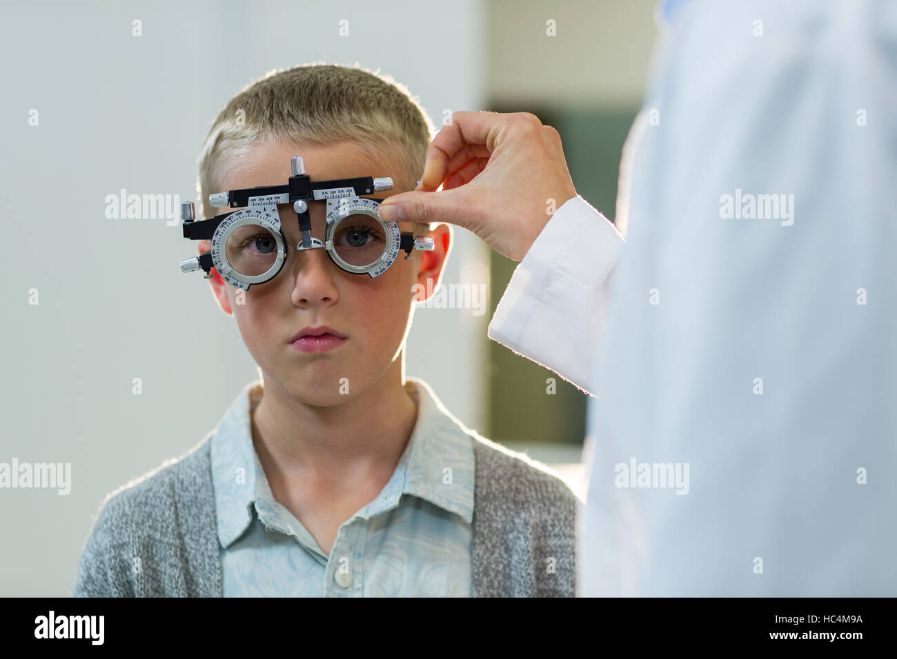 Optometrist examining young patient with phoropter Stock Photo