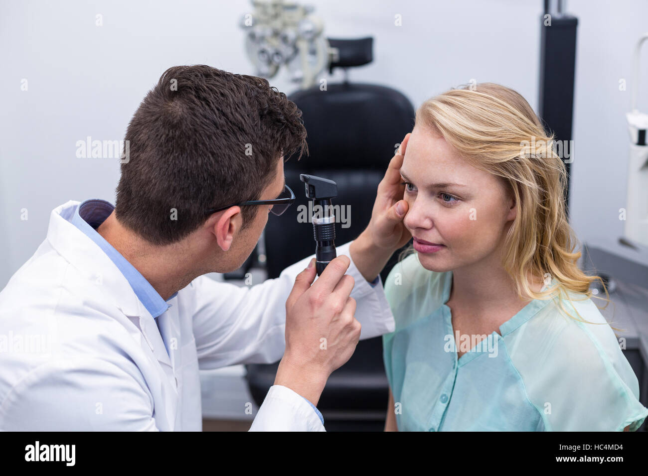 Optometrist examining female patient through ophthalmoscope Stock Photo Alamy
