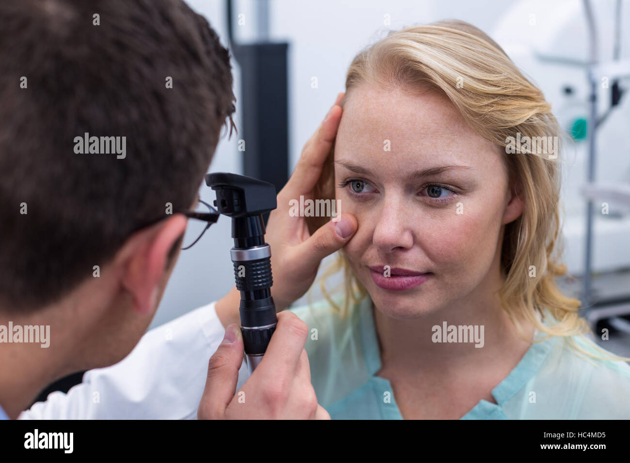Optometrist examining female patient through ophthalmoscope Stock Photo