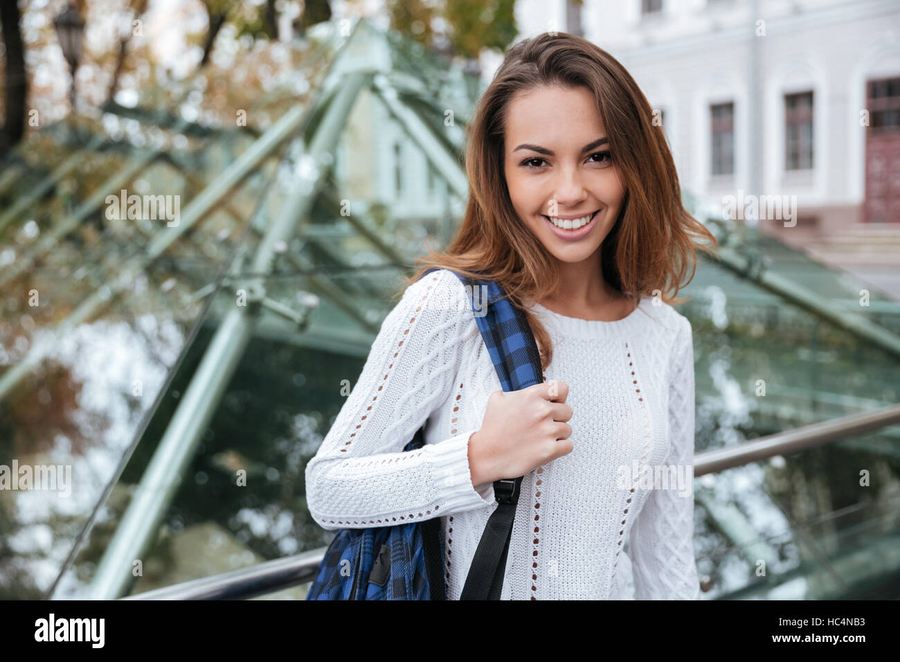 Portrait of cheerful attractive young woman with backpack in the city ...
