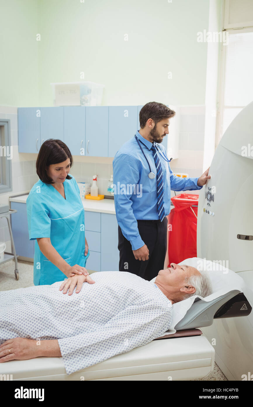 A patient is loaded into an mri machine while doctor and technician