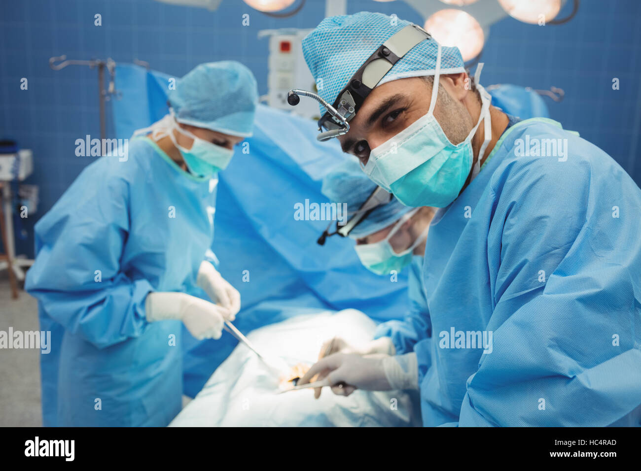 Surgeon looking at camera while colleagues performing operation Stock ...