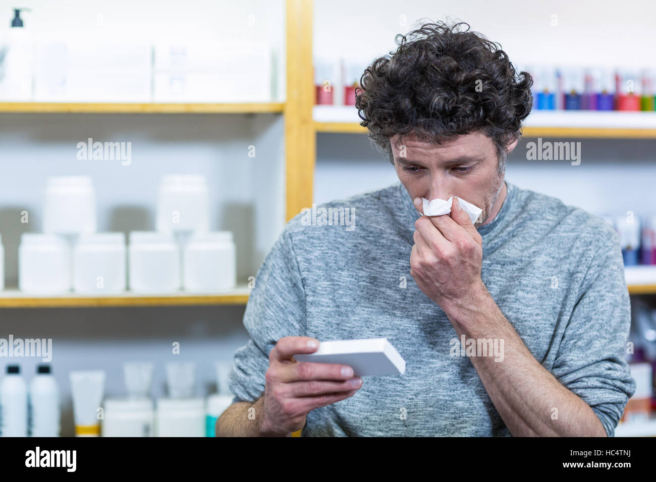 Customer checking medicine box while sneezing Stock Photo