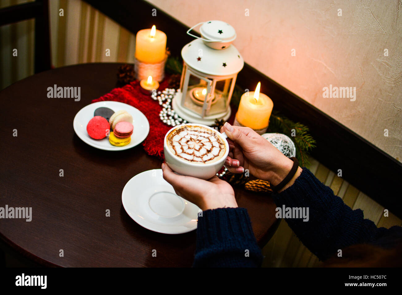 Girl holding cup of cappuccino and dessert macaroons on plate. Stock Photo