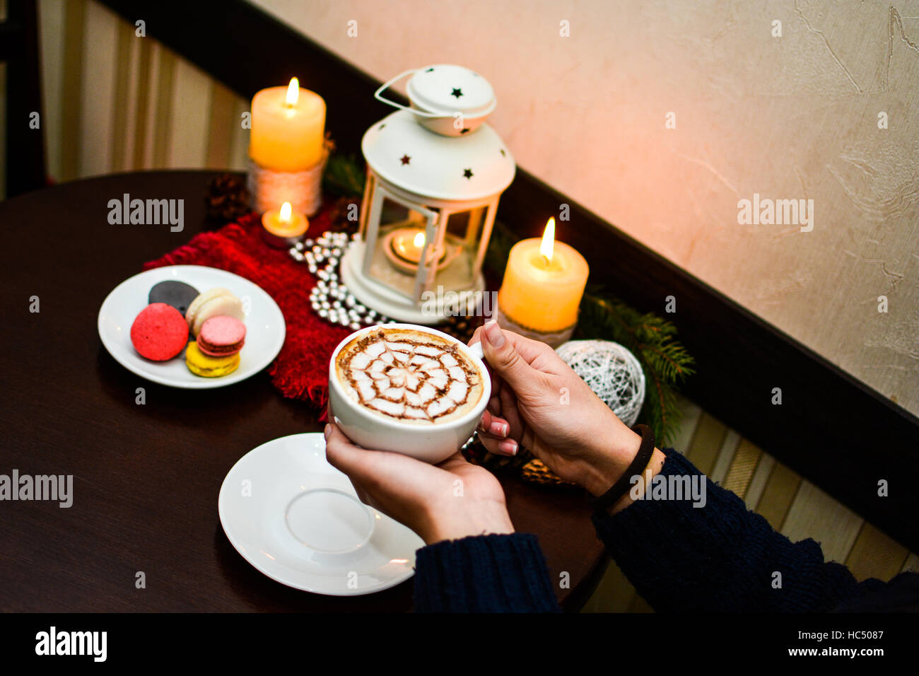 Girl holding cup of cappuccino and dessert macaroons on plate. Stock Photo