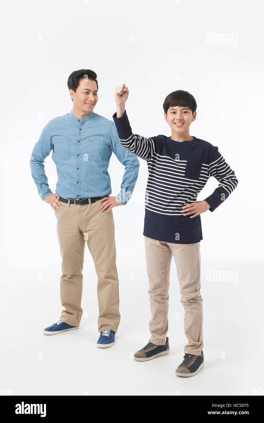 Smiling middle aged father standing with hands on his waist, smiling adolescent son standing cheering Stock Photo