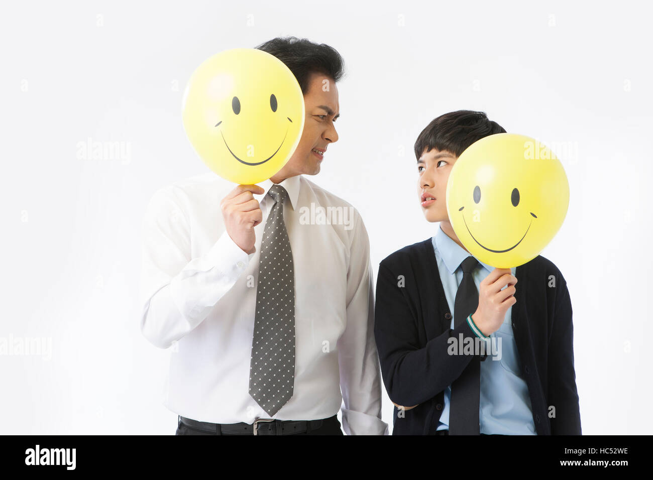 Father and son holding smiling faces frowing their faces Stock Photo