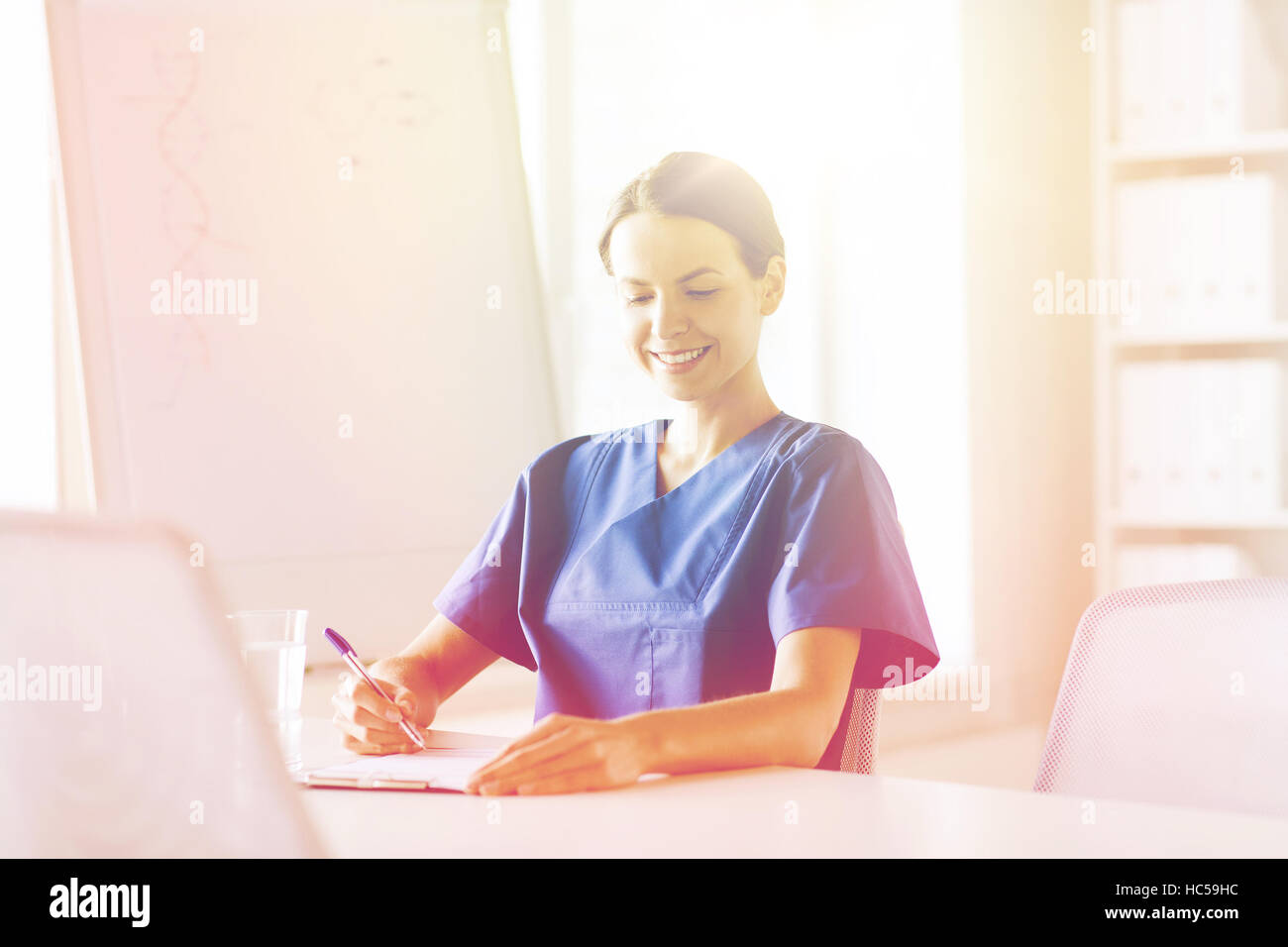 happy female doctor or nurse writing to clipboard Stock Photo - Alamy