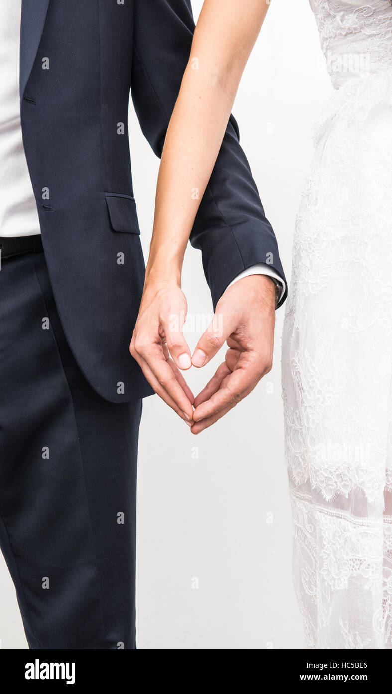 Just married couple holding hands and making heart shape with fingers Stock Photo