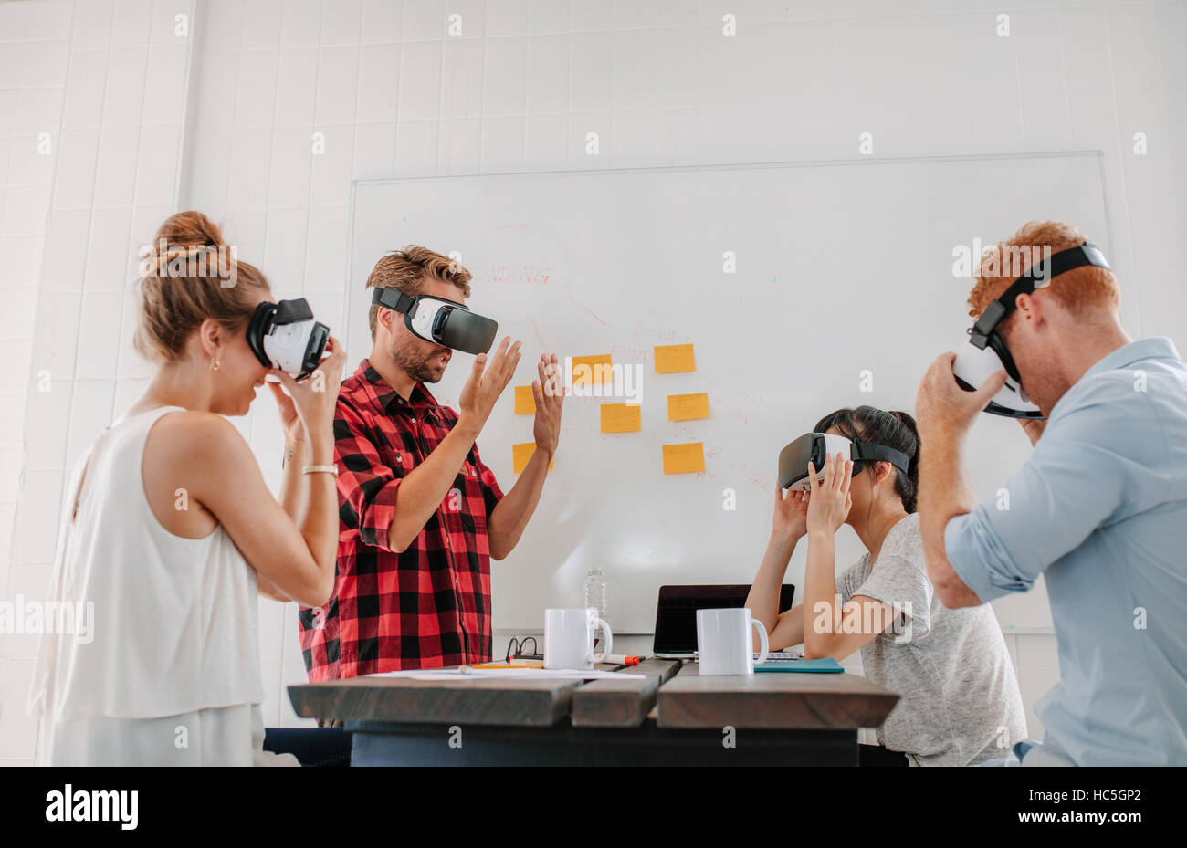 Business people using virtual reality goggles in meeting in office. Team of developers testing virtual reality headset. Stock Photo