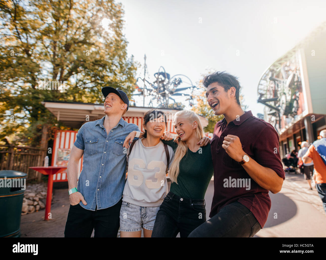 Group of friends enjoying a walk together in amusement park. Young men and women having fun together. Stock Photo